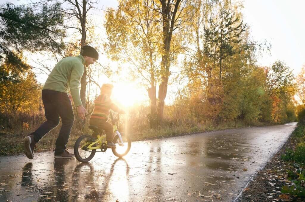 father helping child ride bike