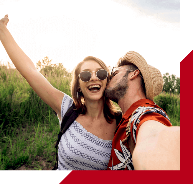 man kissing woman on cheek in a field