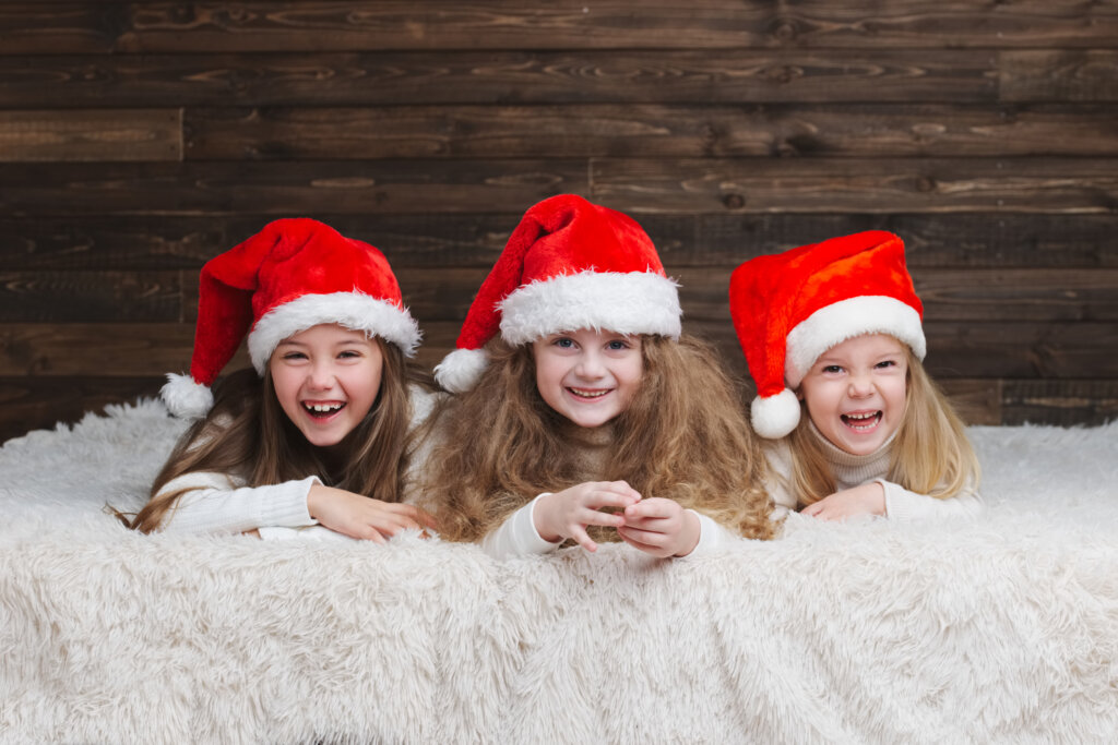 three young girls smiling in santa hats