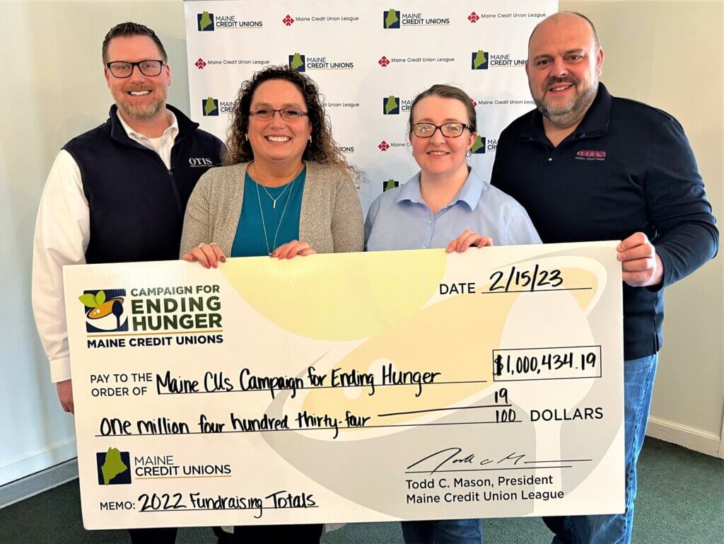 four men and women holding a large check made out to Maine CUs Campaign for Ending Hunger