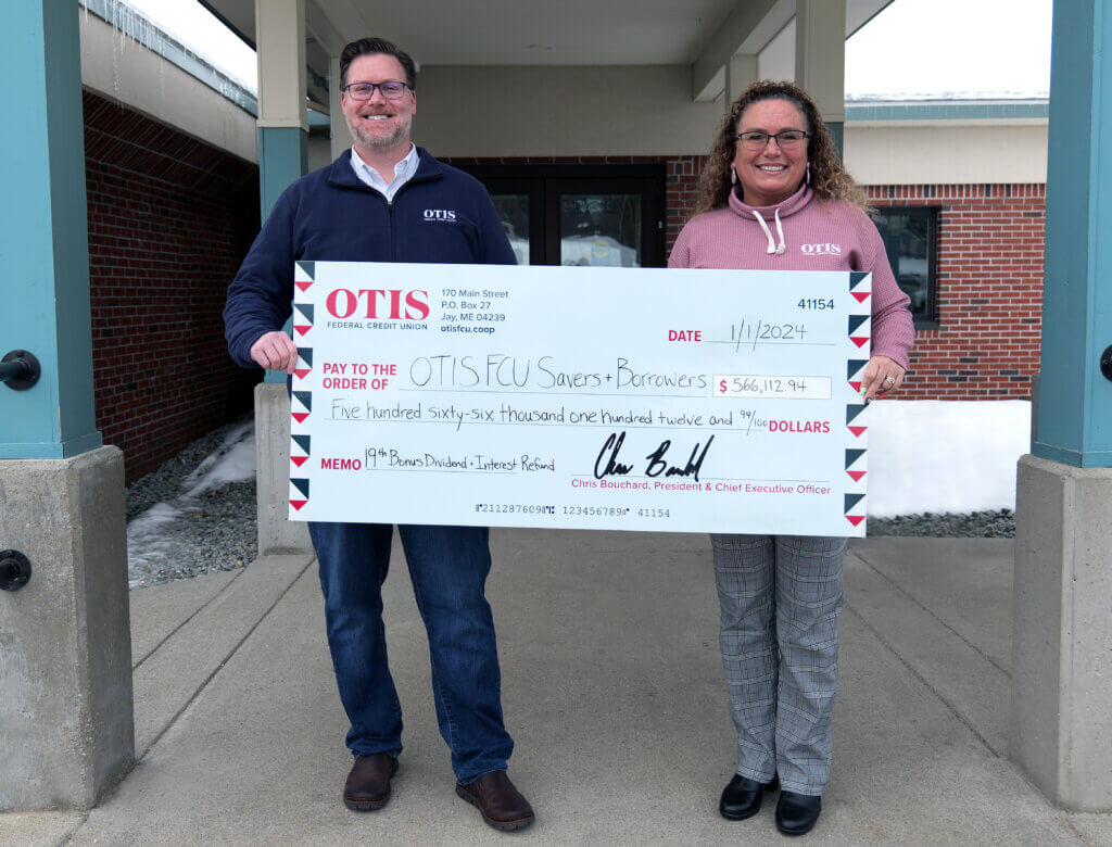 Man and woman with glasses and OTIS shirts holding large check made out to OTIS FCU Savers and Borrowers.