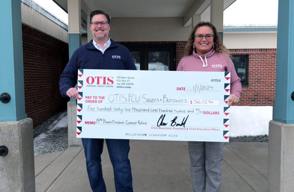 Man and woman with glasses and OTIS shirts holding large check made out to OTIS FCU Savers and Borrowers.