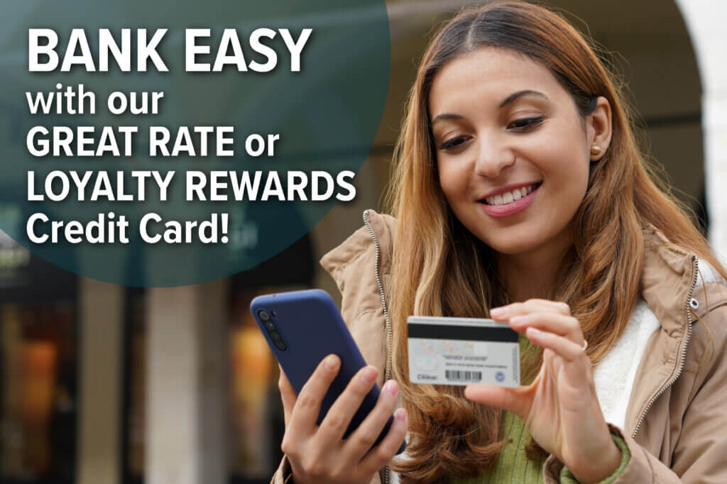 Young woman smiling, looking at phone and credit card. Bank Easy with OTIS FCU's Credit Cards.
