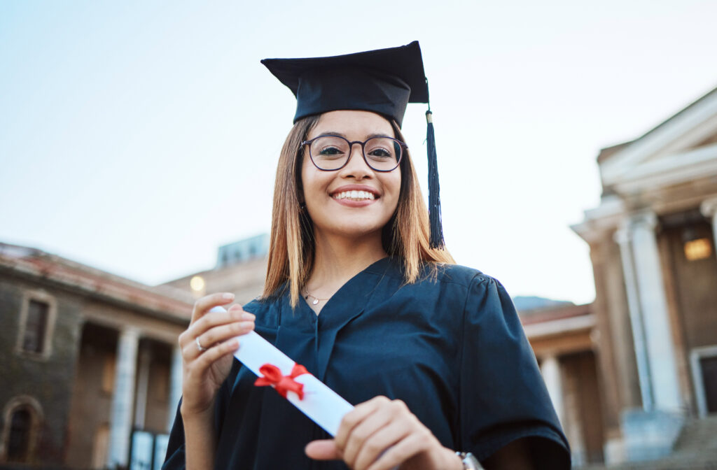 smiling young woman in graduation attire holding diploma